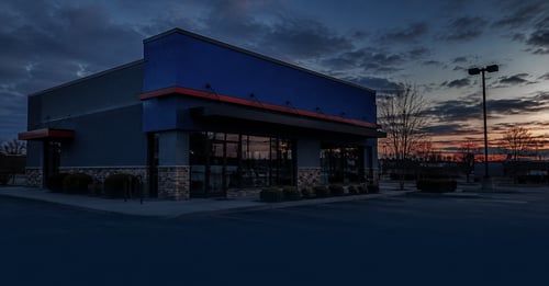An empty, closed-up generic fast-food storefront at dusk, illustrating risky franchises to avoid before buying