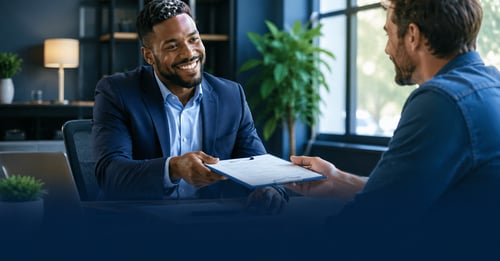 A loan officer handing keys to a new business owner, representing getting an SBA loan to buy a business